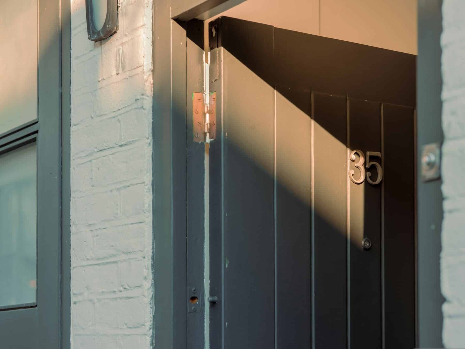 Hand mit Inbusschlüssel an einer Einstellschraube einer Balkontür